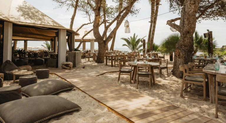 Beachfront restaurant with wooden tables and lounge area on the sand in Santa Eulalia Ibiza near the jet ski center jetski.club
