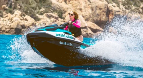 Woman riding a Sea-Doo jet ski fast during a guided jet ski tour with jetski.club in Ibiza turquoise Mediterranean waters