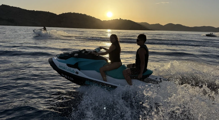 sunset-jet-ski-tour-ibiza-couple-highquality Pareja disfrutando de un tour en moto de agua al atardecer en Ibiza con la isla de Ibiza al fondo